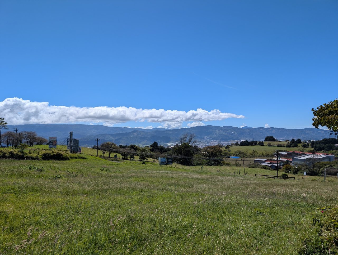 Día despejado: cordillera al fondo, campo verde y nubes bajas