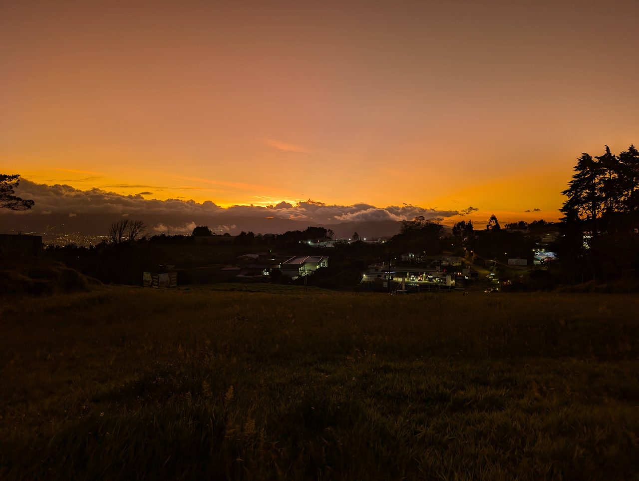 Atardecer naranja sobre el valle de Cartago con luces de la ciudad